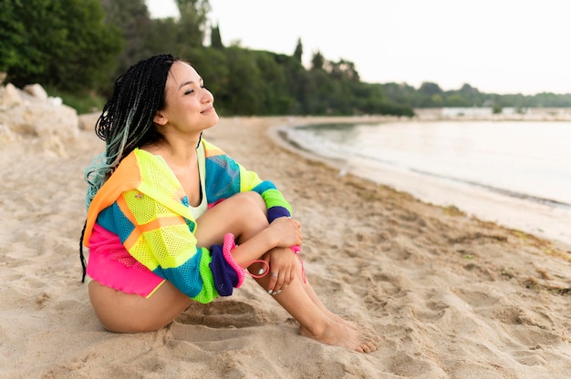 Donna della foto a figura intera che si siede sulla spiaggia