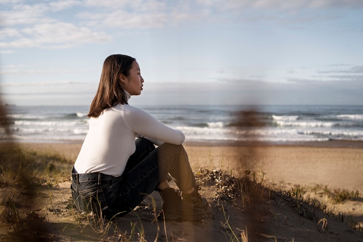 Foto gratuito donna della foto a figura intera che si siede sulla spiaggia