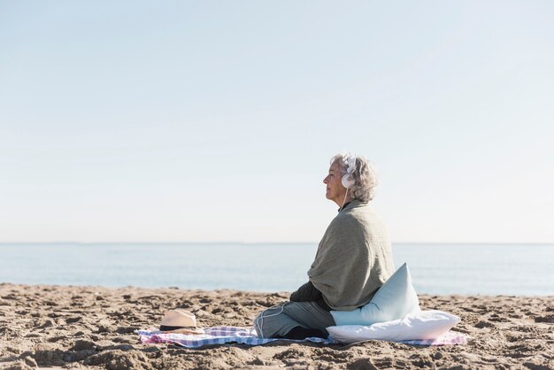 Donna della foto a figura intera con le cuffie sulla spiaggia