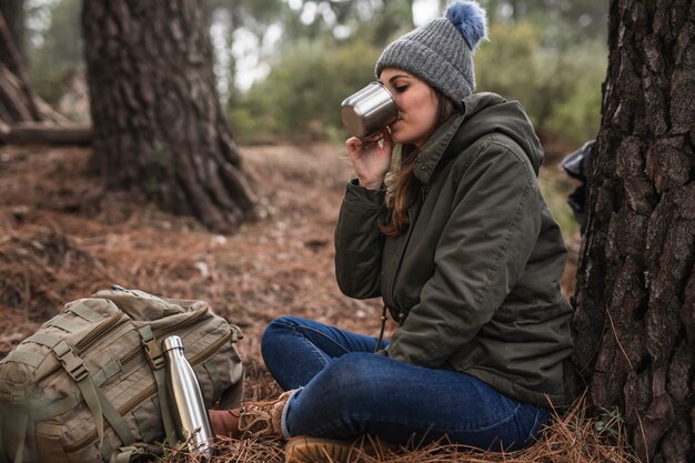 Donna della foto a figura intera vicino a bere dell'albero