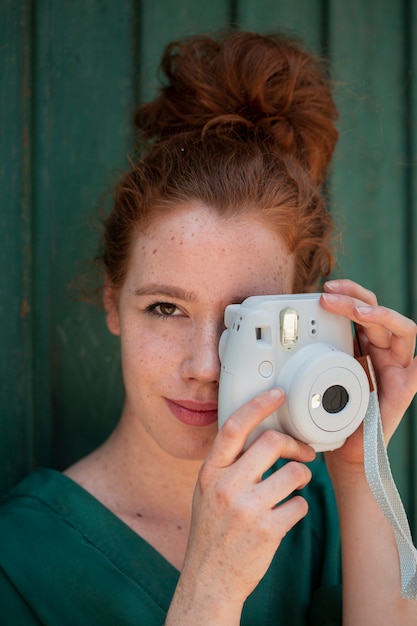 Donna della testarossa del primo piano che per mezzo di una macchina fotografica d'annata