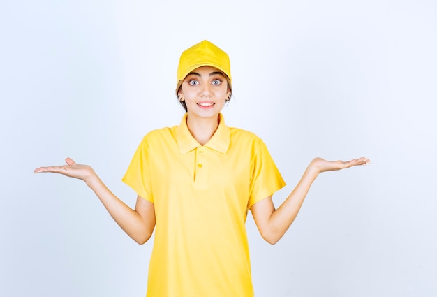 Donna delle consegne in uniforme gialla in piedi e alzando le braccia.