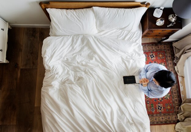 Donna devota con un libro della bibbia che prega dal letto