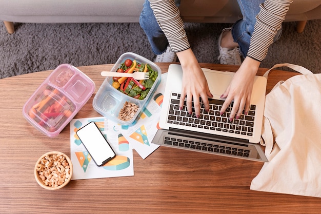 Donna di affari affamata di vista superiore che mangia e che lavora