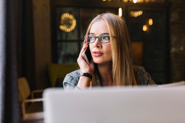 Donna di affari alla moda con il computer portatile in caffetteria accogliente