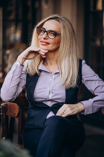 Donna di affari anziana che si siede fuori del caffè