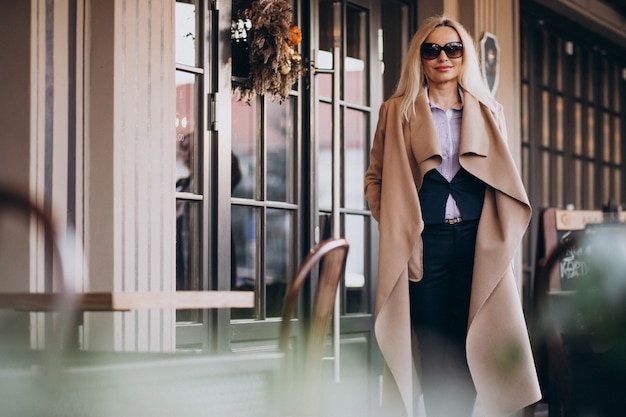 Donna di affari anziana in un cappotto fuori del caffè