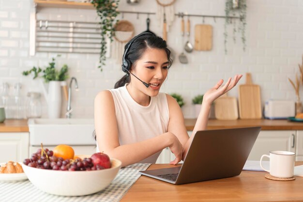 Donna di affari asiatica che usa il computer portatile che parla per il lavoro di riunione di videochiamata da casa