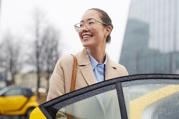 Donna di affari asiatica Taking Taxi in Rainy Street