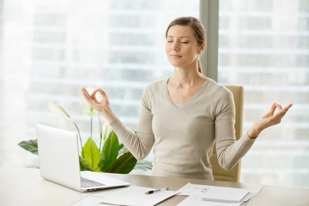 Donna di affari calma che si distende con la ginnastica del respiro