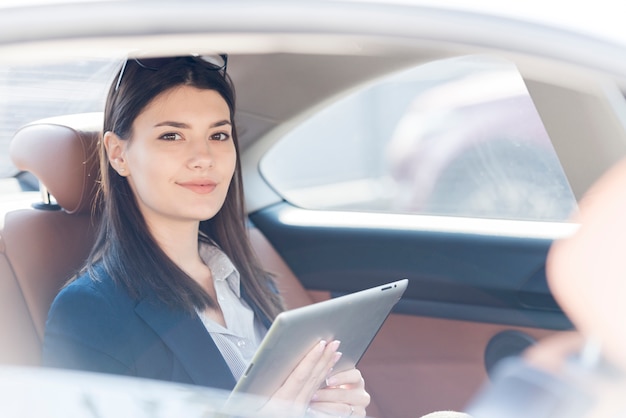 Donna di affari castana che posa dentro un&#39;automobile