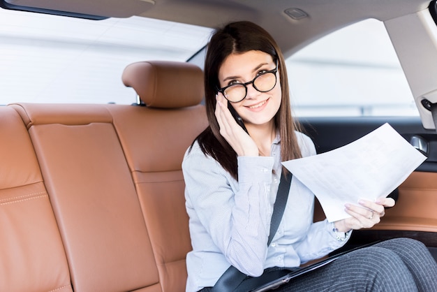 Donna di affari castana che posa dentro un&#39;automobile