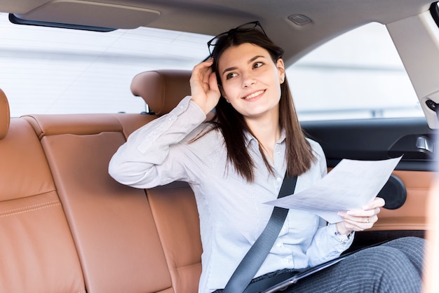 Donna di affari castana che posa dentro un&#39;automobile