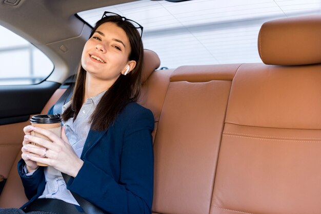 Donna di affari castana che posa dentro un&#39;automobile