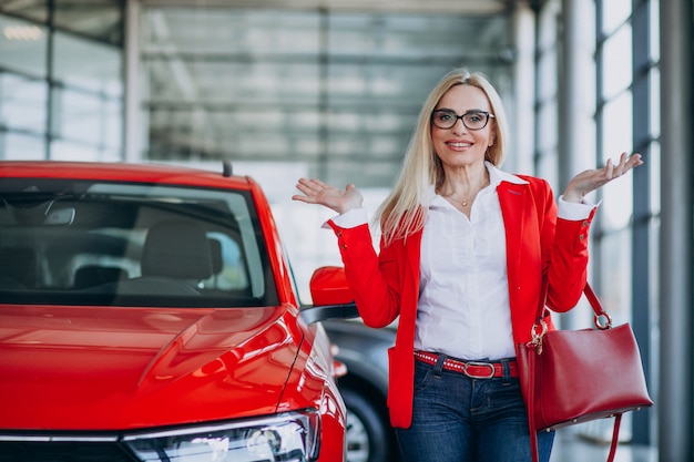 Donna di affari che cerca un cellulare automatico ad una sala d'esposizione dell'automobile