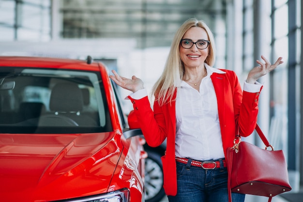 Donna di affari che cerca un cellulare automatico ad una sala d'esposizione dell'automobile