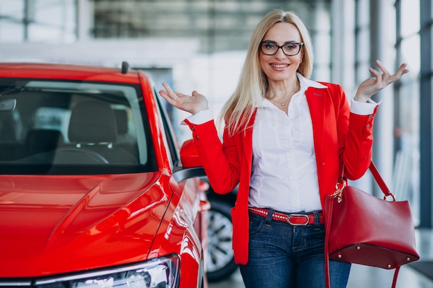 Donna di affari che cerca un cellulare automatico ad una sala d'esposizione dell'automobile