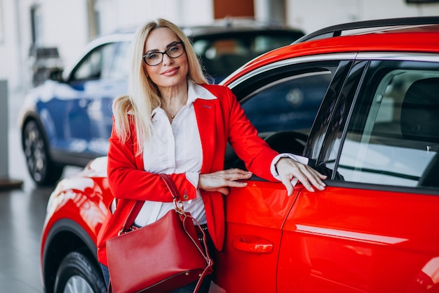 Donna di affari che cerca un cellulare automatico ad una sala d'esposizione dell'automobile