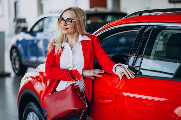 Donna di affari che cerca un cellulare automatico ad una sala d'esposizione dell'automobile