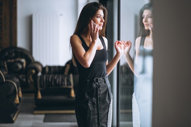 Donna di affari che comunica sul telefono che fa una pausa la finestra