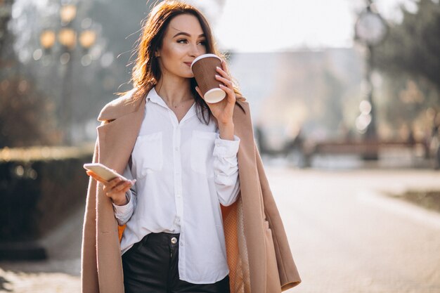 Donna di affari che comunica sul telefono e che beve caffè