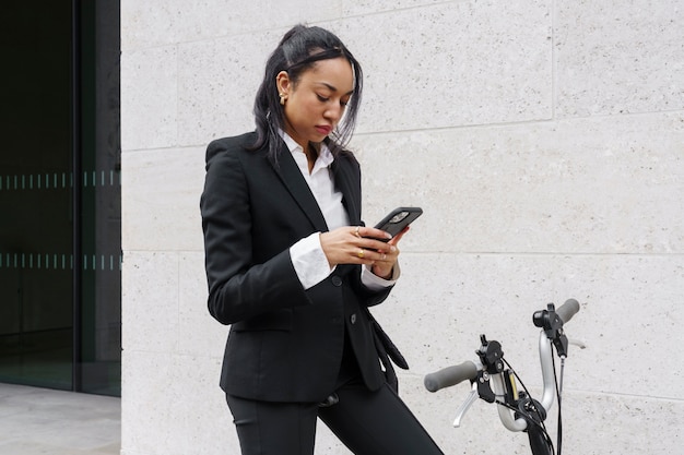 Donna di affari che controlla smartphone su una bici