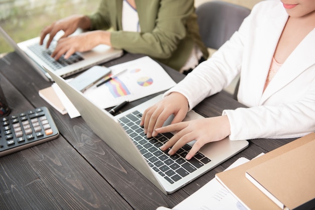 Donna di affari che digita sul computer portatile alle donne del posto di lavoro che lavorano nella tastiera della mano dell'ufficio domestico.