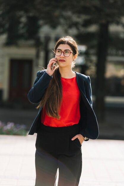 Donna di affari che fa chiamata di telefono all&#39;aperto