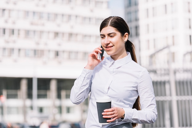 Donna di affari che fa chiamata di telefono all&#39;aperto