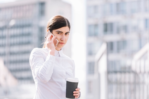 Donna di affari che fa chiamata di telefono all&#39;aperto