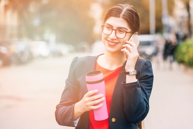 Donna di affari che fa chiamata di telefono all&#39;aperto