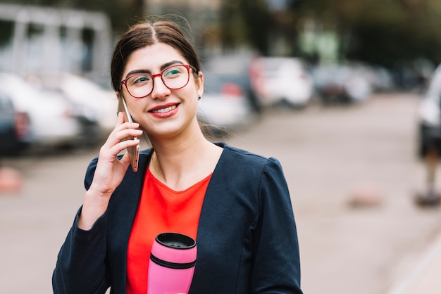 Donna di affari che fa chiamata di telefono all&#39;aperto