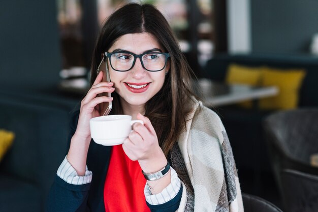 Donna di affari che fa chiamata di telefono in caffetteria