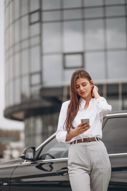 Donna di affari che fa una pausa l&#39;automobile e che per mezzo del telefono