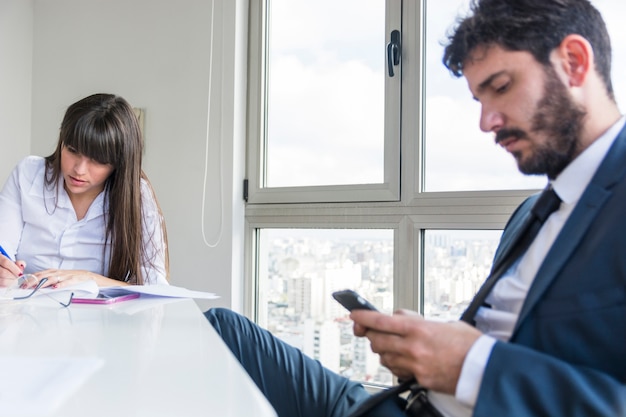 Donna di affari che lavora nell&#39;ufficio con l&#39;uomo che per mezzo della compressa digitale