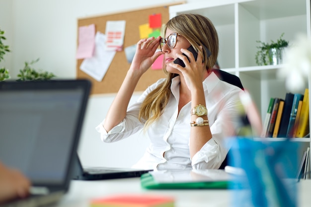 Donna di affari che lavorano con il telefono mobile nel suo ufficio.