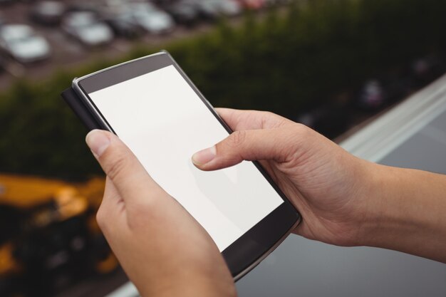 Donna di affari che per mezzo del telefono cellulare al balcone dell'ufficio