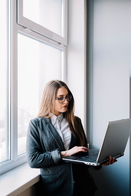 Donna di affari che scrive sulla tastiera del computer portatile