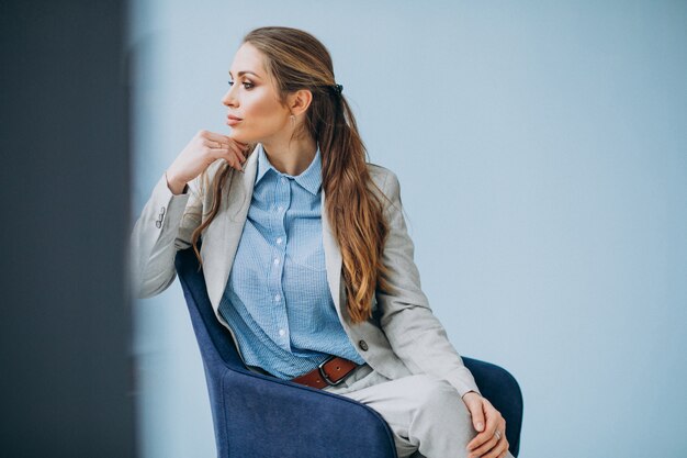 Donna di affari che si siede nella sedia ad un ufficio