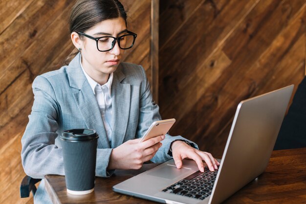 Donna di affari con il computer portatile e lo smartphone in caffetteria