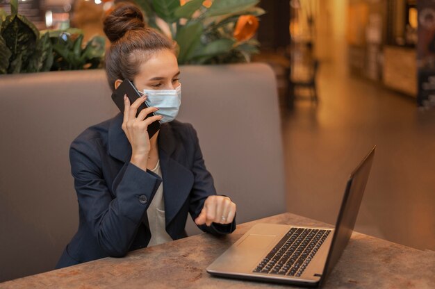 Donna di affari con mascherina medica che lavora al computer portatile