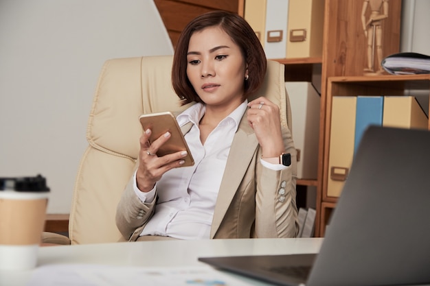 Donna di affari convenzionale che utilizza telefono nell'ufficio