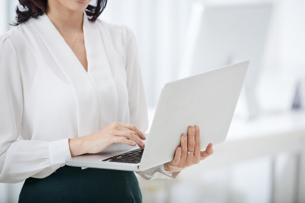 Donna di affari del raccolto che per mezzo del computer portatile