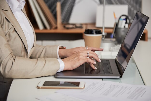 Donna di affari del raccolto che per mezzo del computer portatile