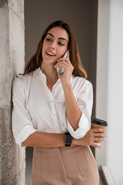 Donna di affari di smiley parlando al telefono mentre beve il caffè