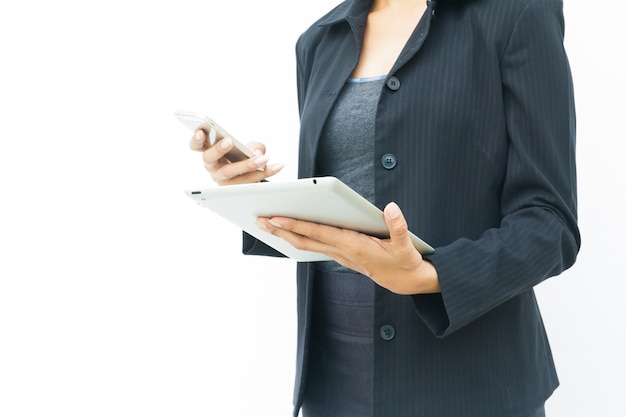 Donna di affari in abito scuro, utilizzando il suo tablet e telefono cellulare su sfondo bianco, con spazio di copia