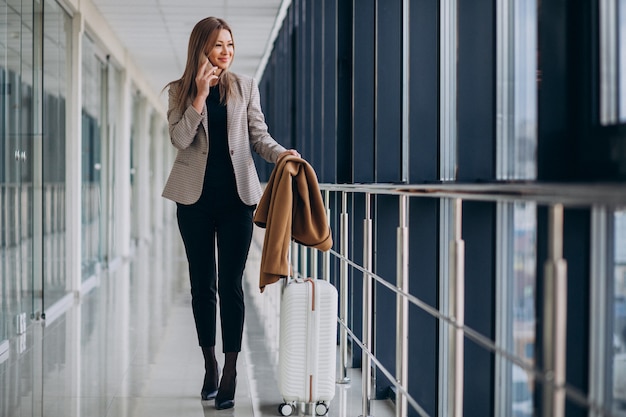 Donna di affari in terminale con la borsa di viaggio che parla sul telefono