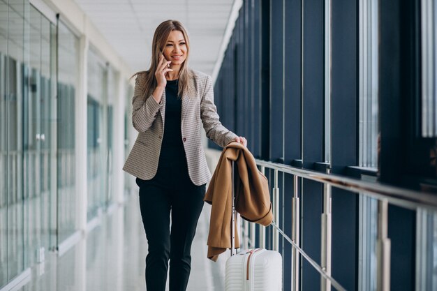 Donna di affari in terminale con la borsa di viaggio che parla sul telefono