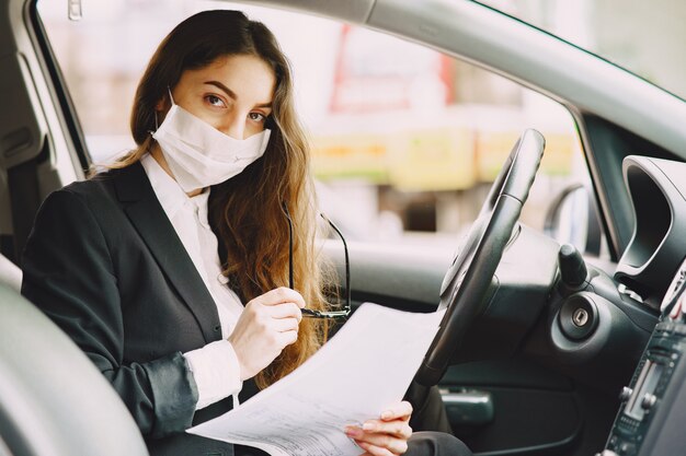 Donna di affari in una maschera nera che si siede dentro un'automobile