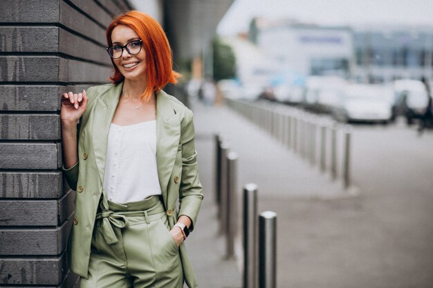 Donna di affari in vestito verde che fa una pausa la parete